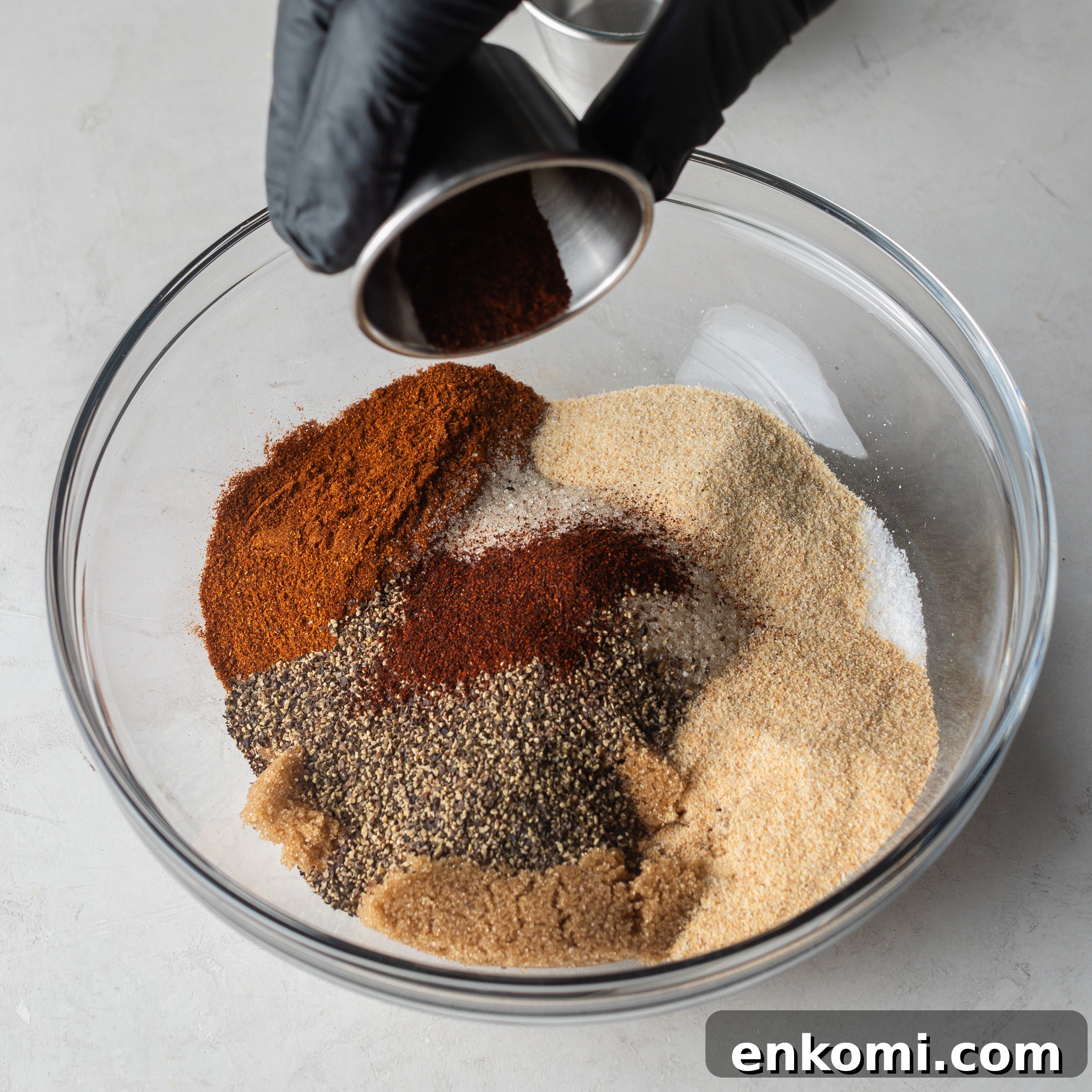Homemade BBQ Rub Recipe for Tender, Flavorful Grilling 4 BBQ seasoning ingredients in a large glass mixing bowl.