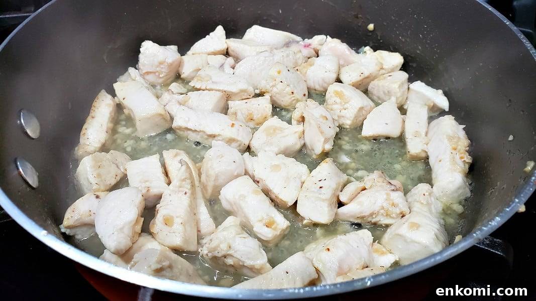diced chicken and garlic cooking in a large pan.