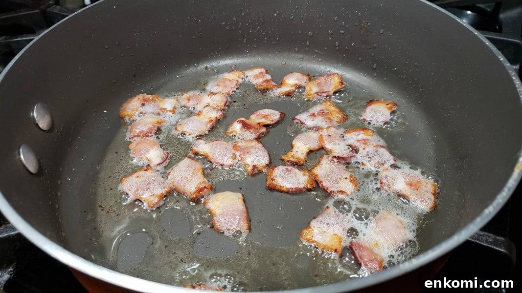 bacon pieces frying in a large pan.