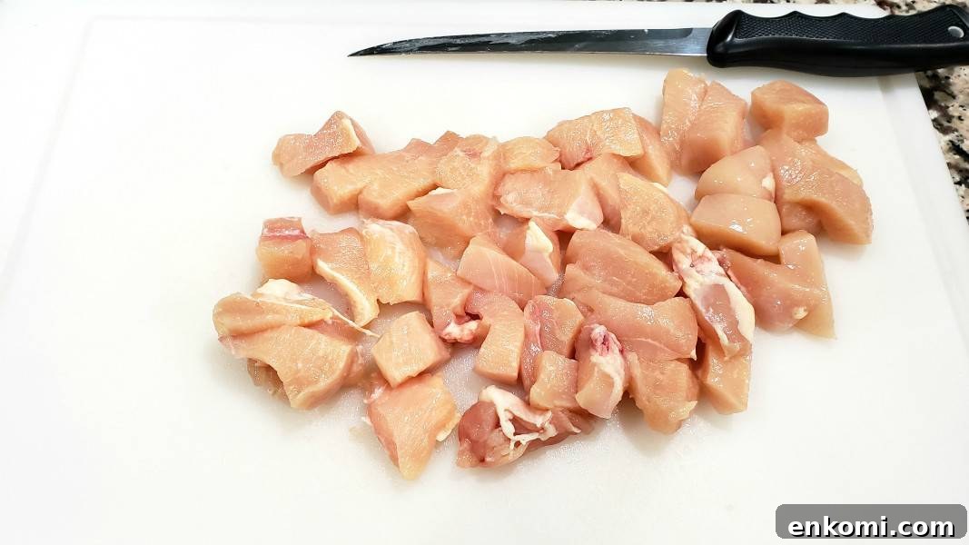bonless chicken diced on a cutting board.