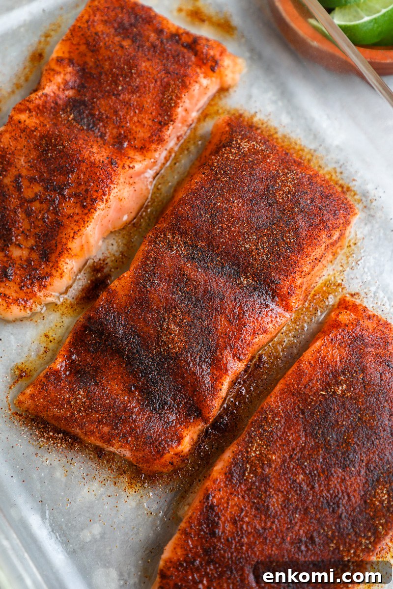 A clear baking dish filled with salmon fillets brushed with honey and sprinkled with chipotle seasoning