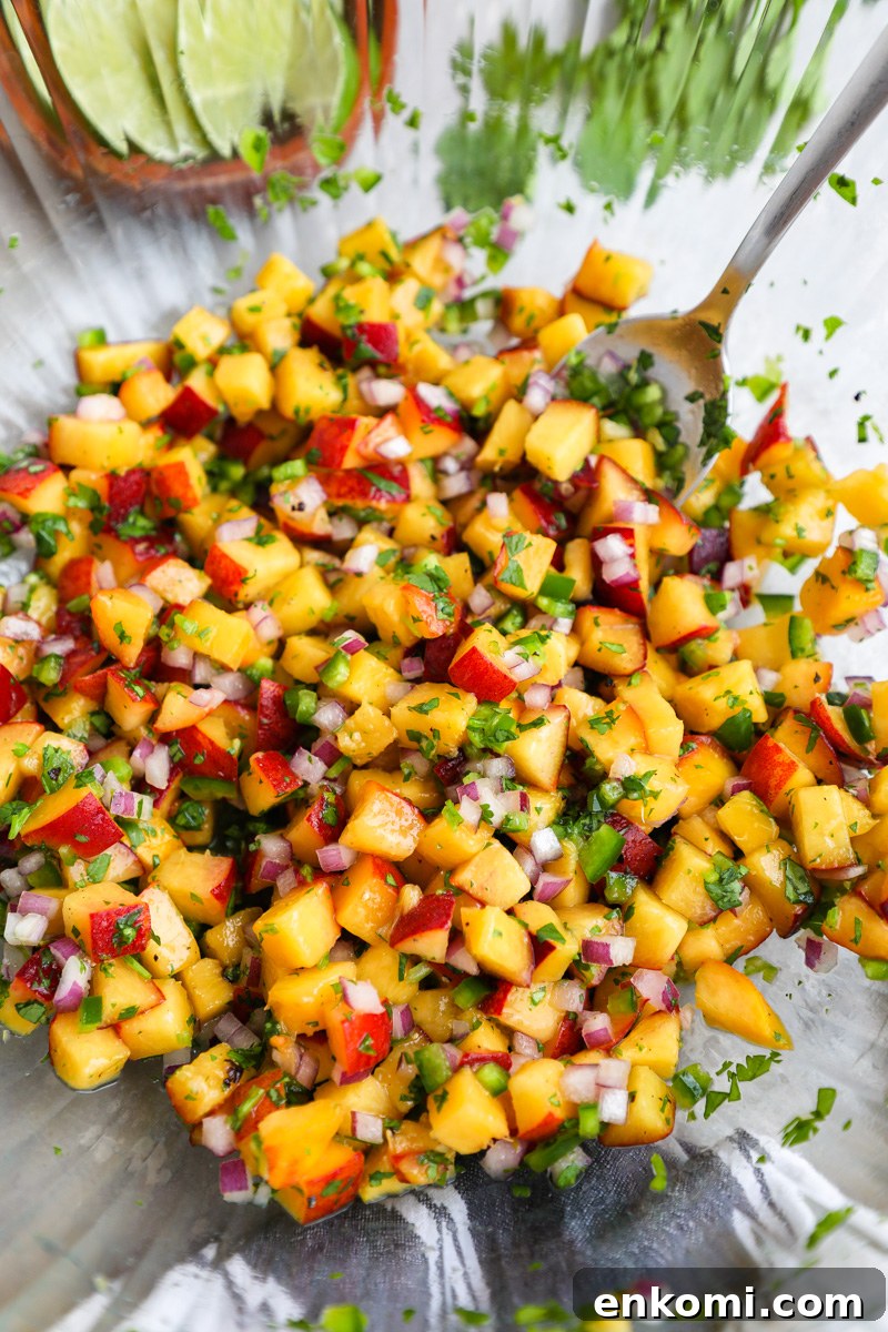 A clear mixing bowl filled with fresh peach salsa