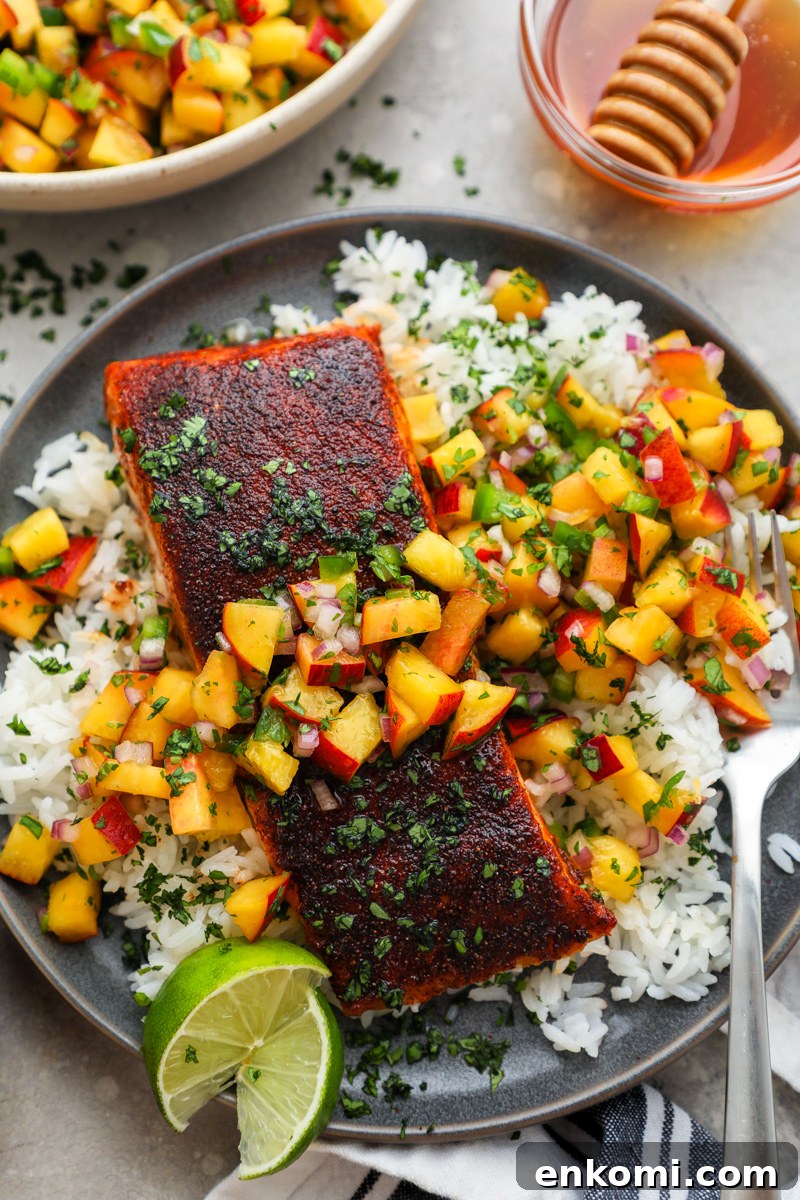 A large serving plate filled with chipotle salmon fillets topped with peach salsa served with lime wedges