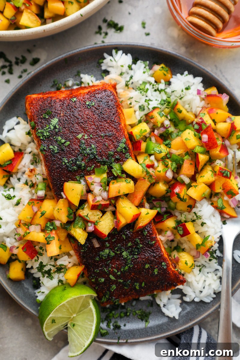 Roasted chipotle salmon sitting on a bed of white rice topped with fresh peach salsa