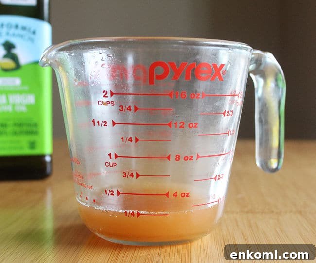 Two cup glass measuring pitcher filled with apple cider vinegar.