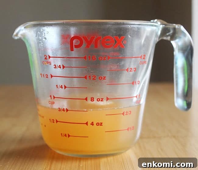 Glass measuring cup filled with gold liquid.