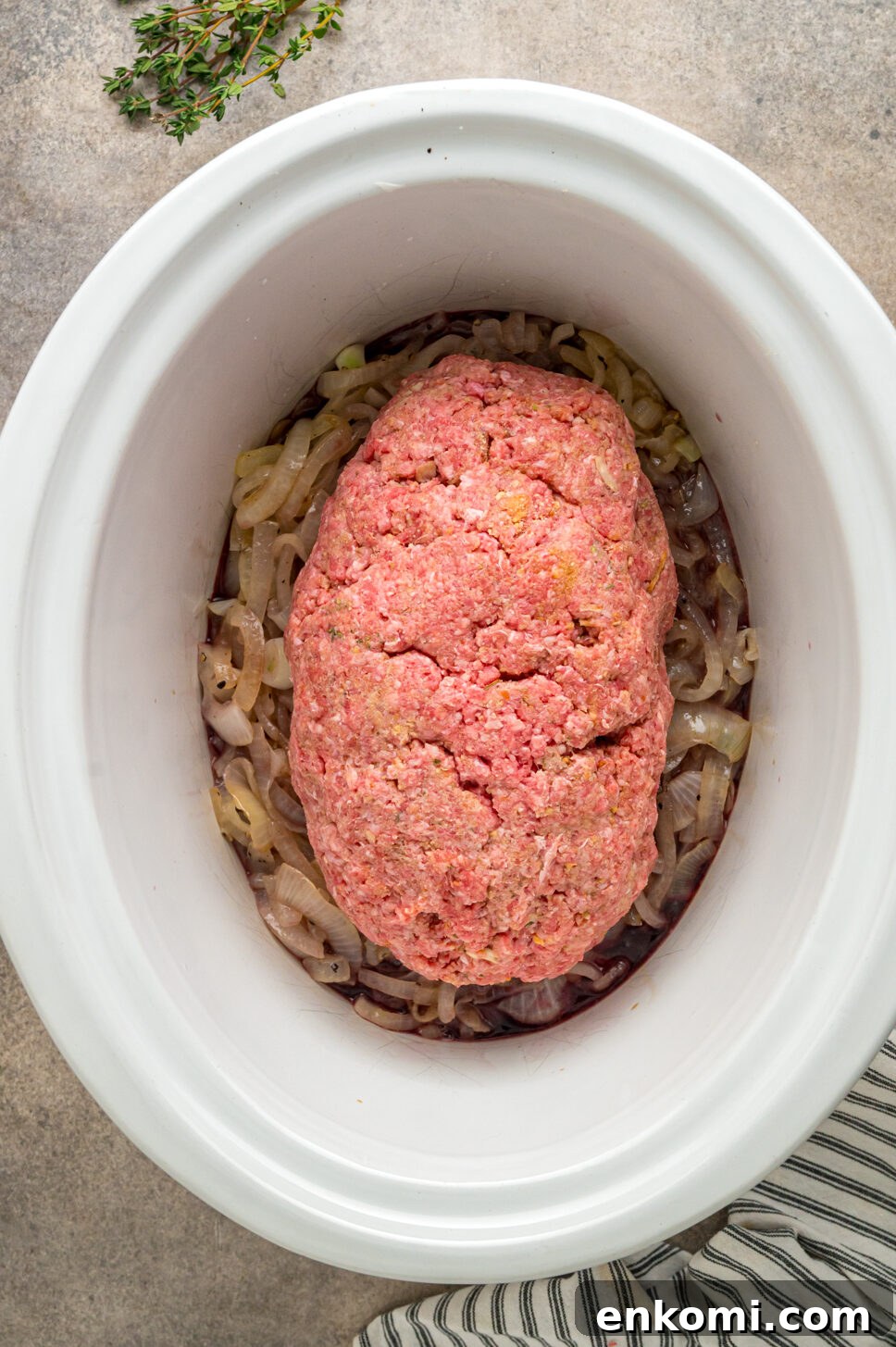 French Onion Meatloaf with Caramelized Onions and Gruyère 4 Formed meatloaf on top of onions in a slow cooker.