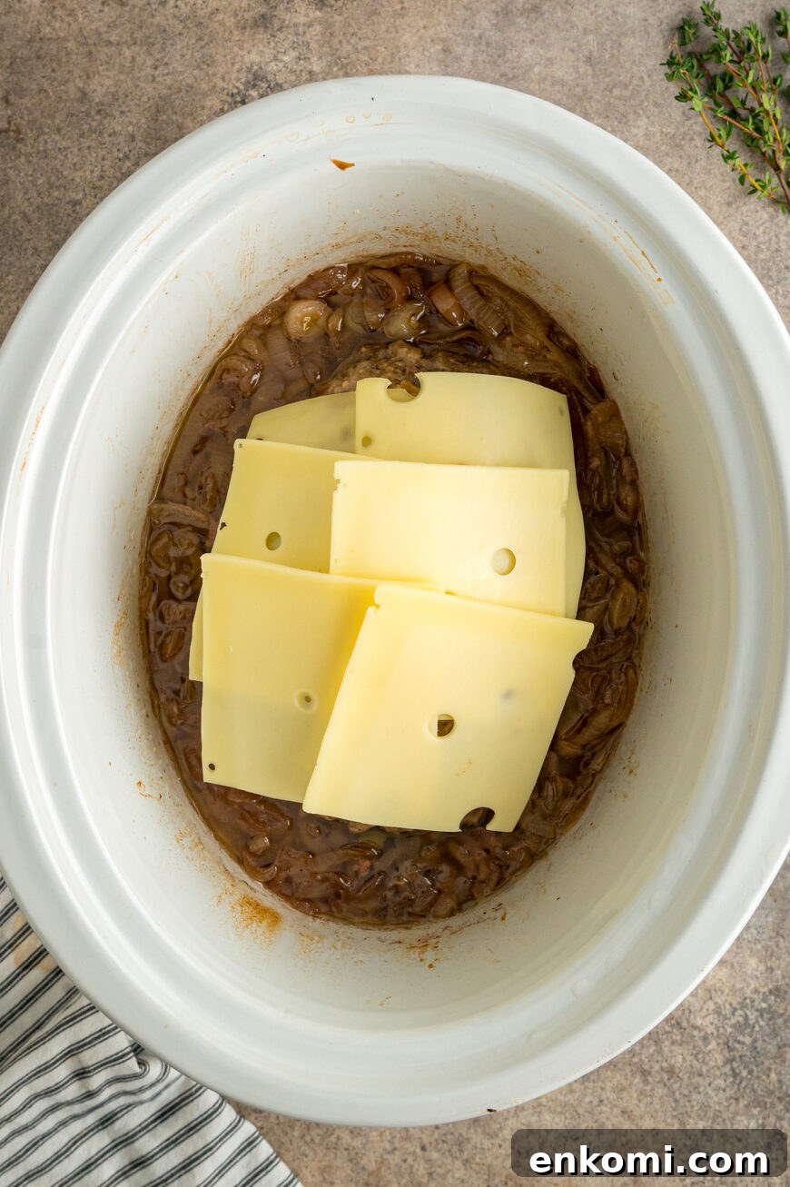 French Onion Meatloaf with Caramelized Onions and Gruyère 5 Slices of Swiss cheese on top of meatloaf in a slow cooker.
