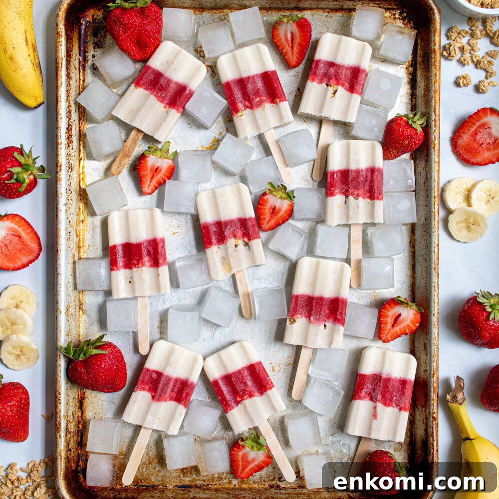 Cottage Cheese & Apple Breakfast Bowls with Granola and Honey 6 Sheet tray full of red and white parfait popsicles and ice cubes surrounded bu sliced strawberries, bananas, and bits of granola.