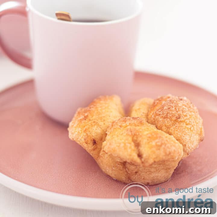 A square photo of a pink plate with a cup of coffee and a monkey bread muffin in front of it.