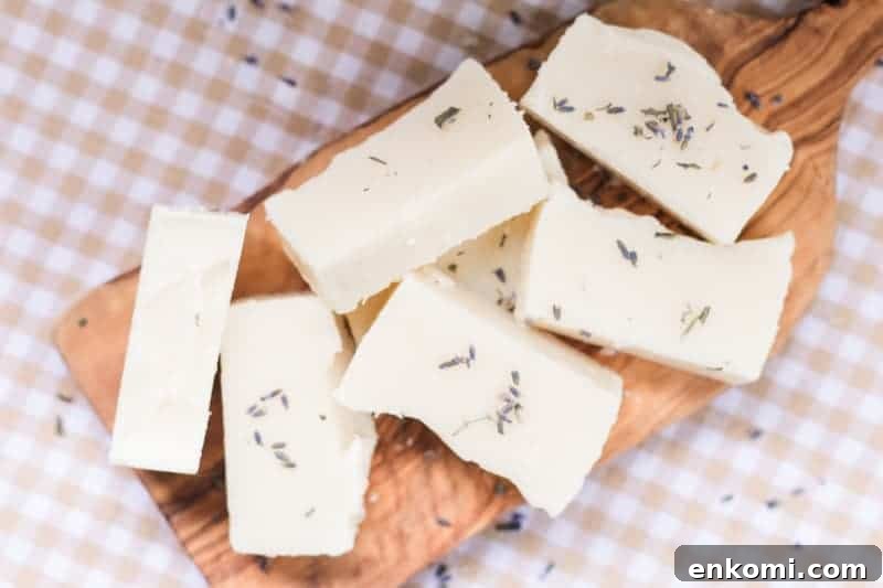Soothing Homemade Baby Soap Bar Recipe 3 Cold-process soap bars on wooden board with lavender buds.