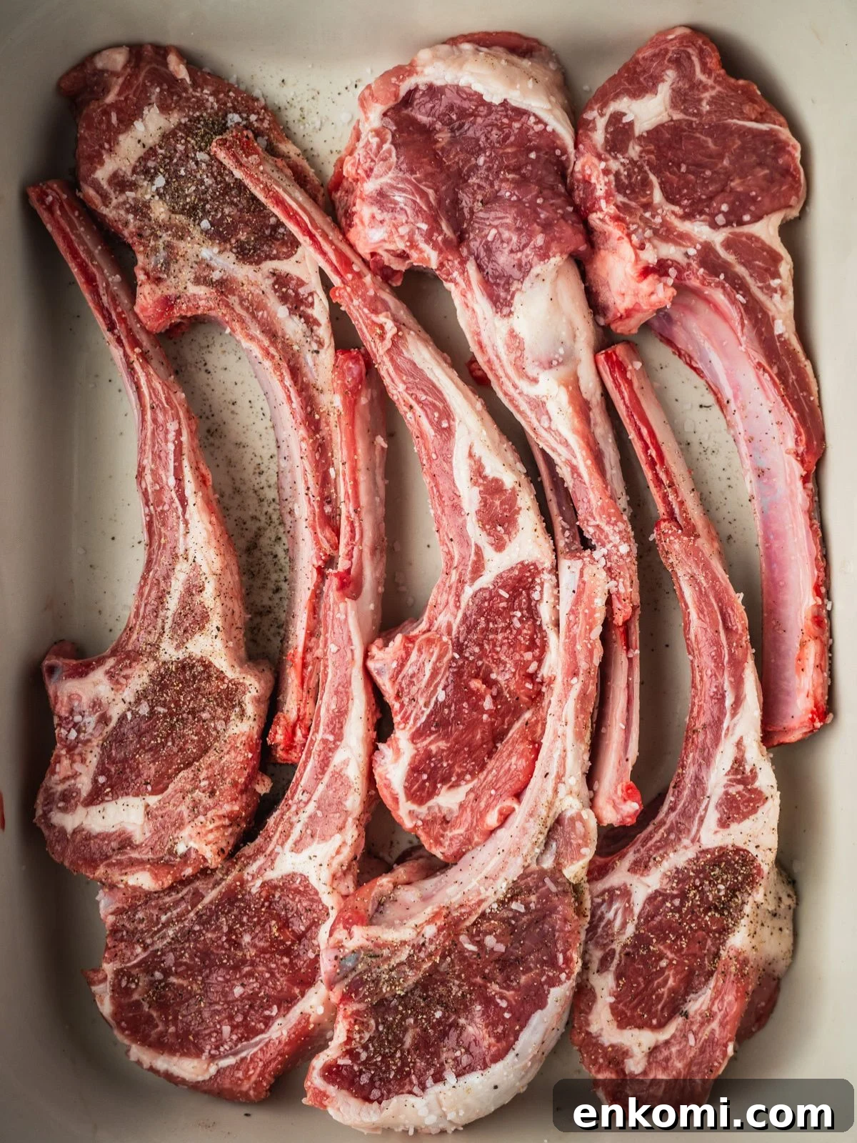 Grilled or Pan-Seared Marinated Greek Lamb Chops 4 Lamb chops in a tray seasoned with salt and pepper.