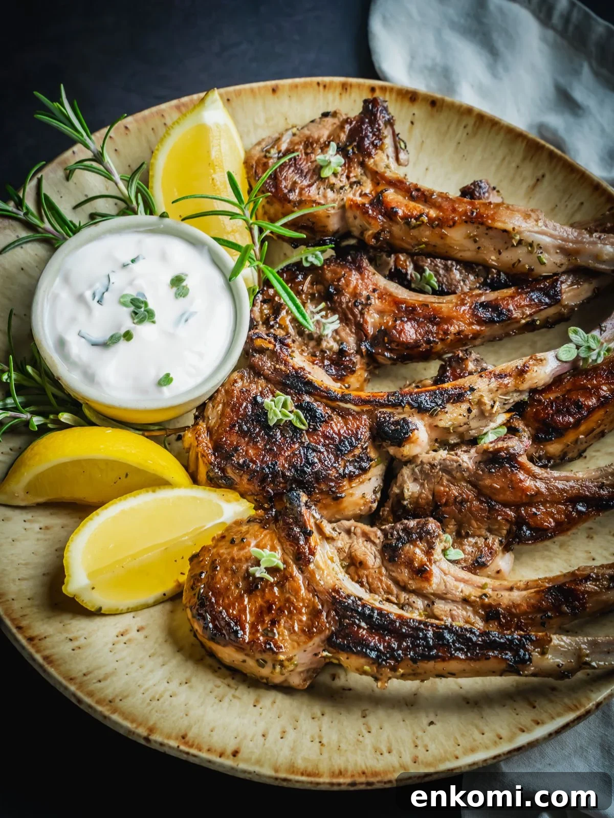 Grilled or Pan-Seared Marinated Greek Lamb Chops 8 Grilled and marinated Greek lamb chops on a platter with rosemary and lemon wedges.