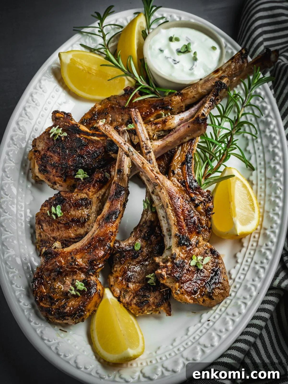 Grilled or Pan-Seared Marinated Greek Lamb Chops 9 Grilled and marinated Greek lamb chops on a platter with rosemary and lemon wedges.