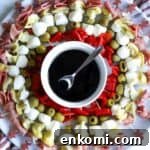 Charcuterie skewers on platter with balsamic glaze in bowl in center.