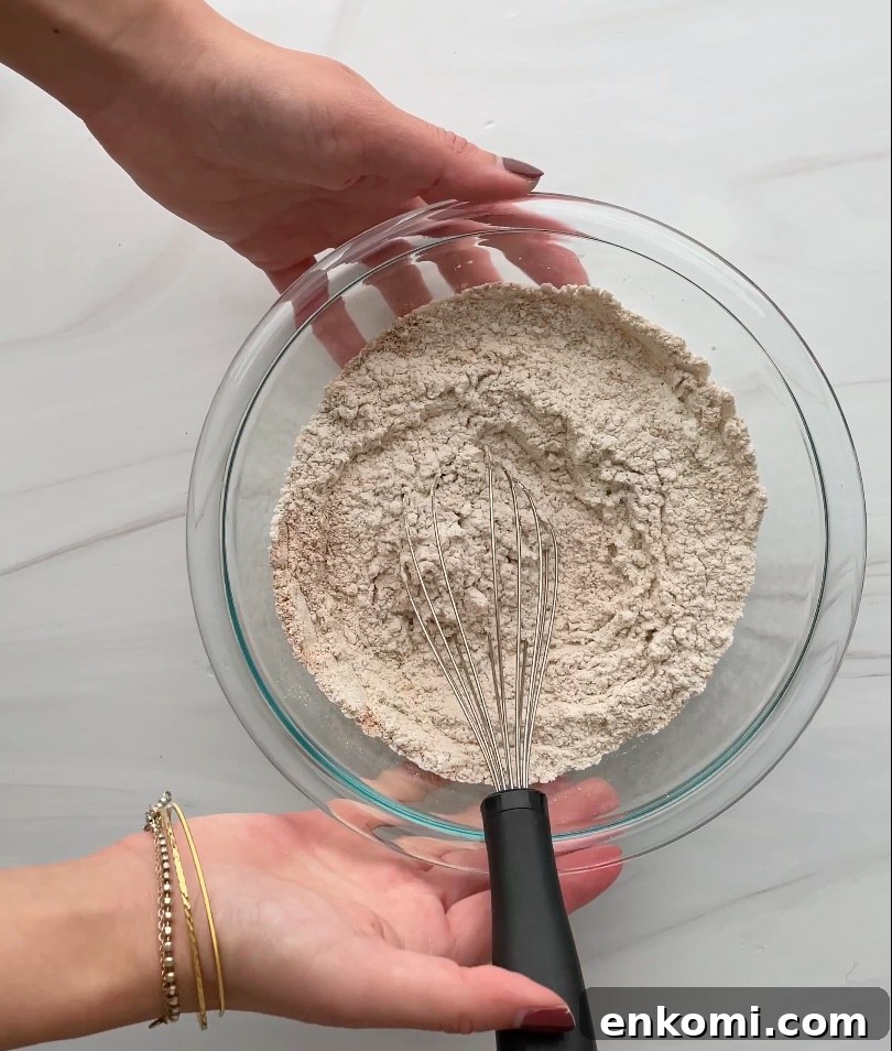 Dry ingredients with a whisk in a glass bowl.