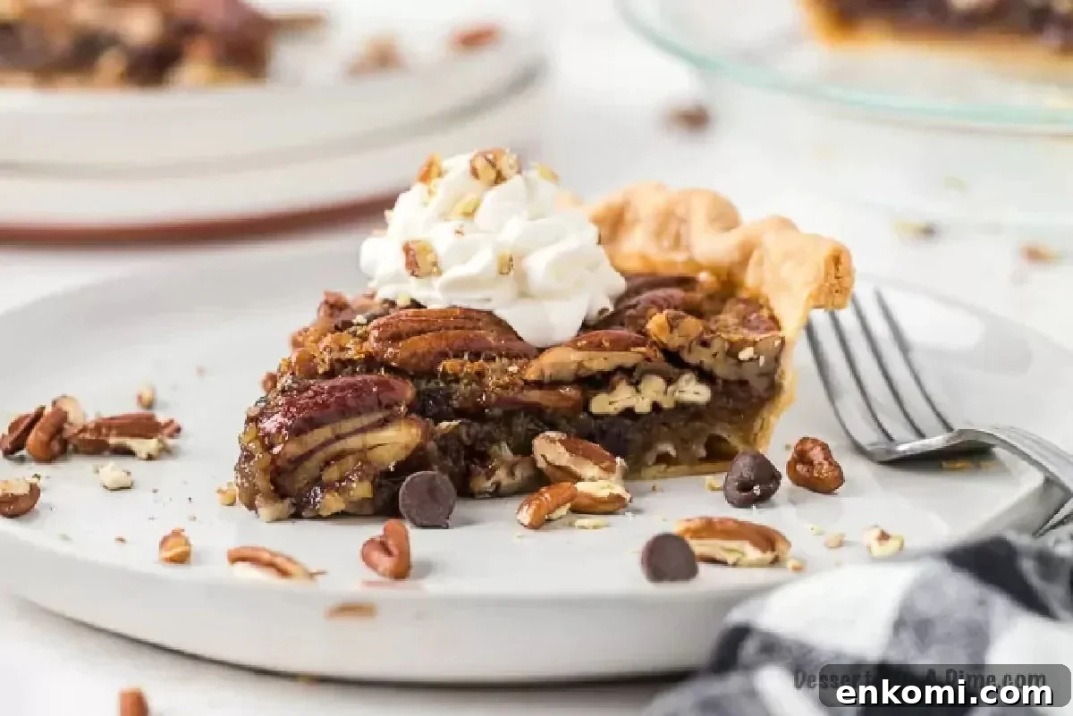 Slice of chocolate pecan pie on a plate with whipped cream. 
