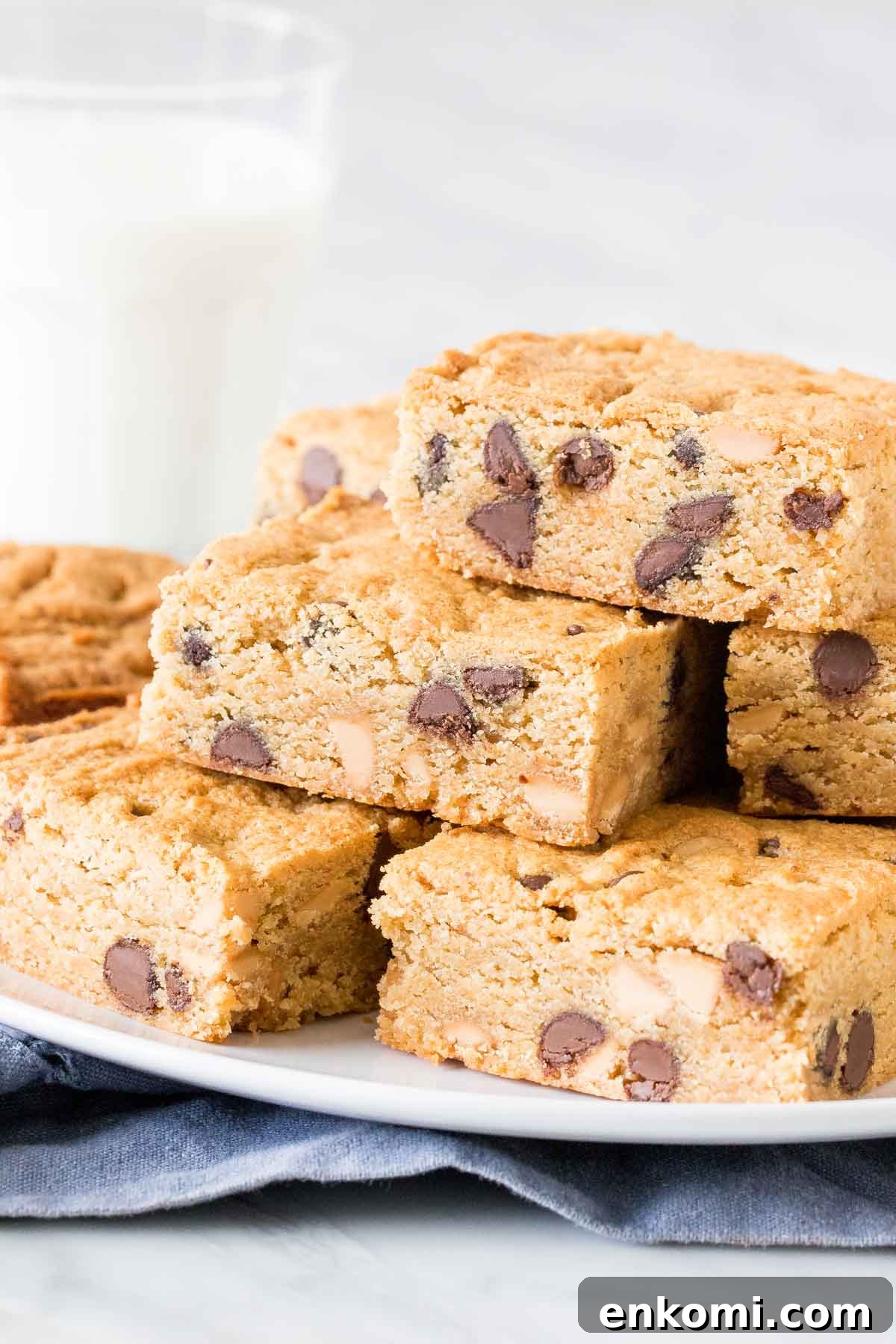 Plate of peanut butter cookie bars stacked one top of each other with glass of milk. 