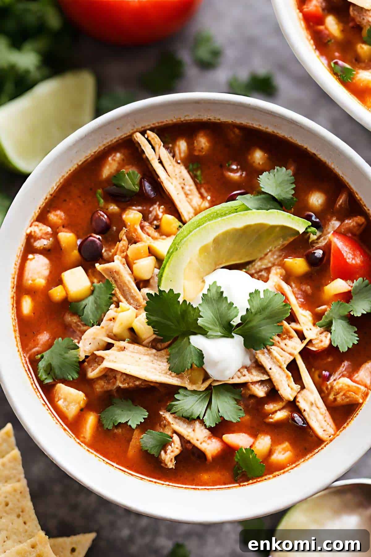 A bowl of Mexican chicken tortilla soup topped with avocado and cilantro.