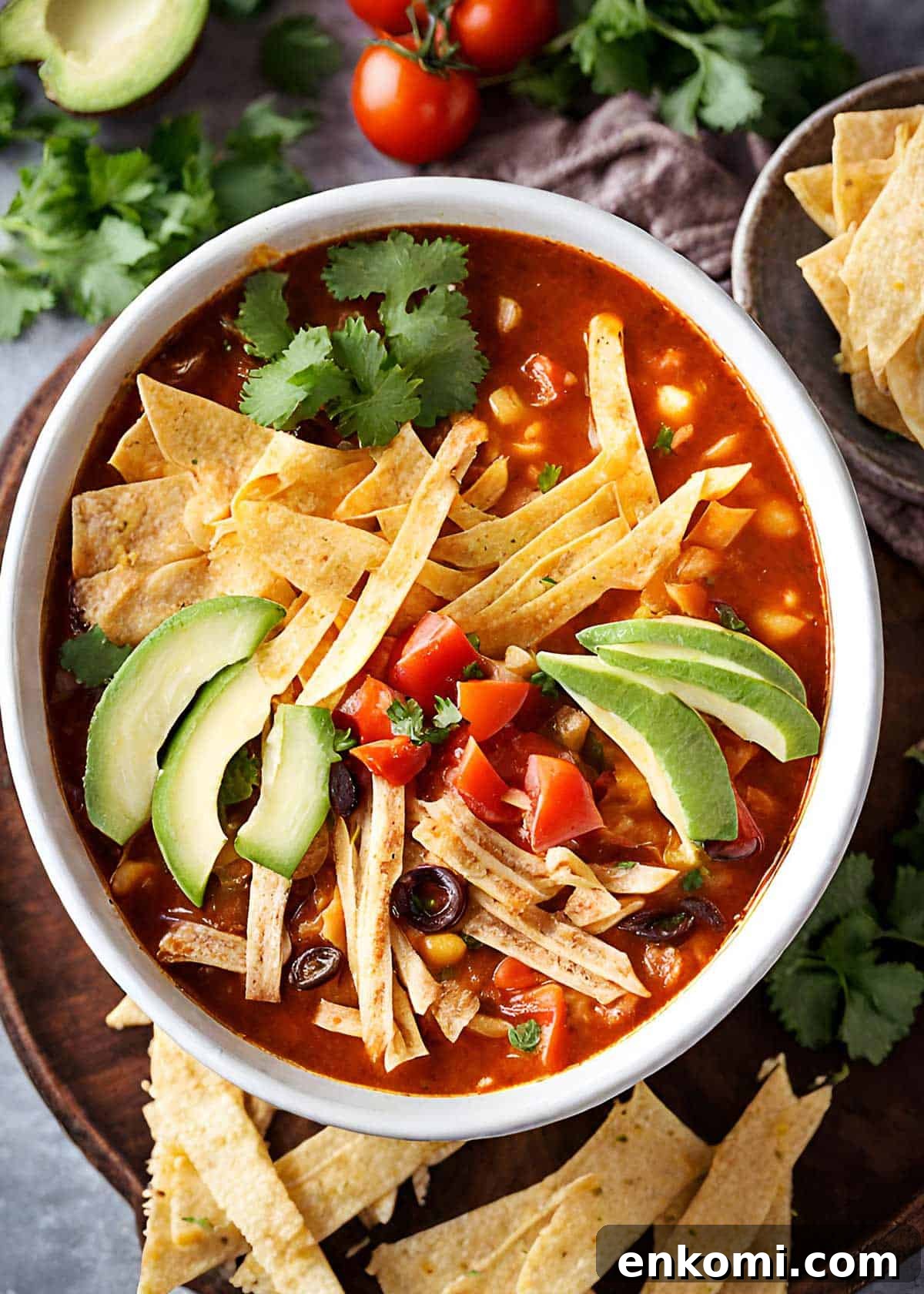 Mexican chicken tortilla soup served in a bowl with avocado, tortilla strips, and cilantro.