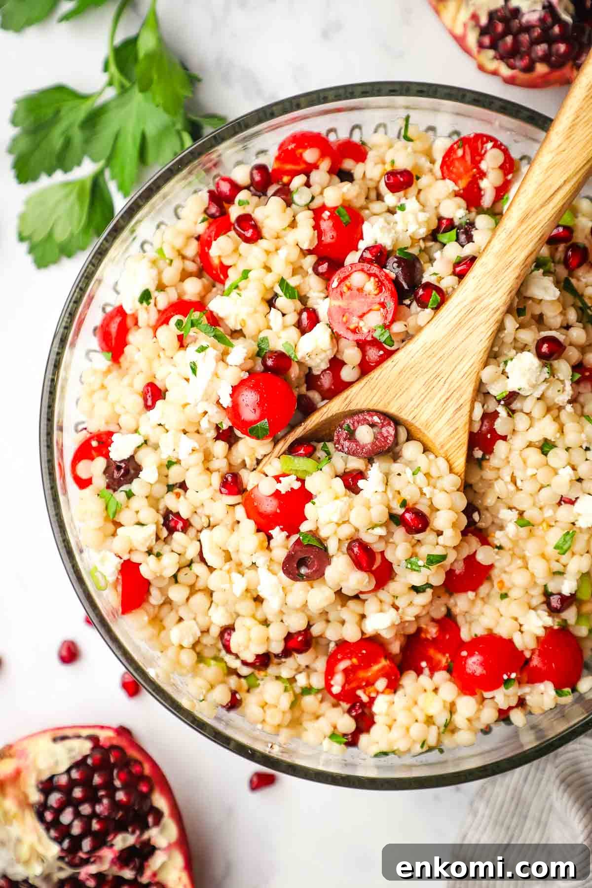 Mediterranean Pearl Couscous Salad with Fresh Herbs & Feta 2 A large serving bowl of Israeli couscous salad with a wooden serving spoon in it.