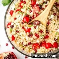 Mediterranean Pearl Couscous Salad with Fresh Herbs & Feta 12 A large serving bowl of Israeli couscous salad with a wooden serving spoon in it.