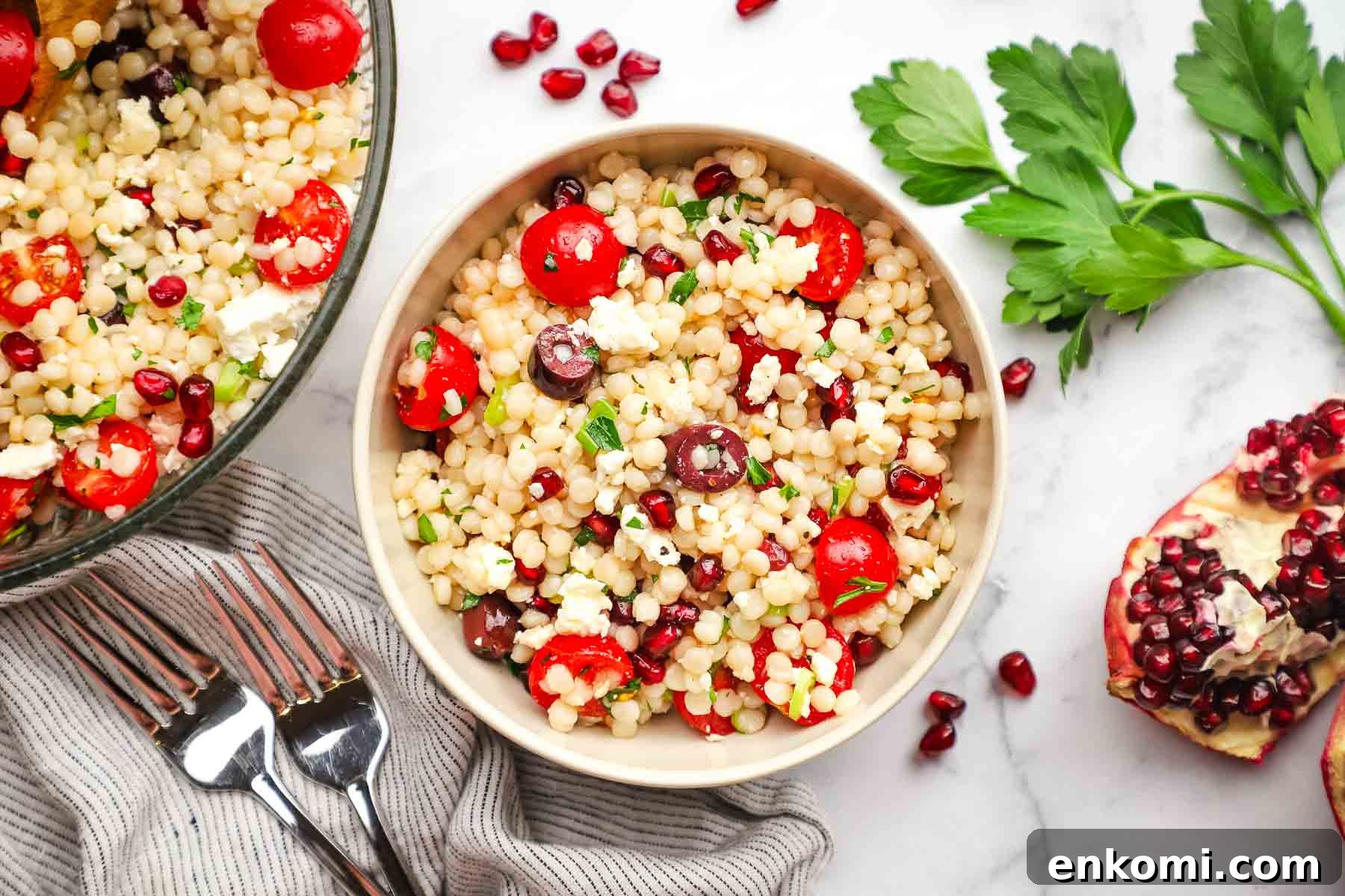 Mediterranean Pearl Couscous Salad with Fresh Herbs & Feta 3 a serving of Mediterranean couscous salad in a bowl with the serving bowl in the background.