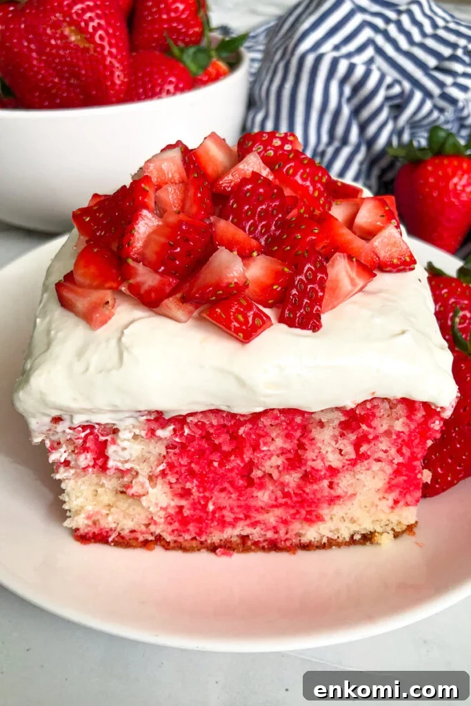 close up shot of a slice of strawberry poke cake with diced strawberries on top