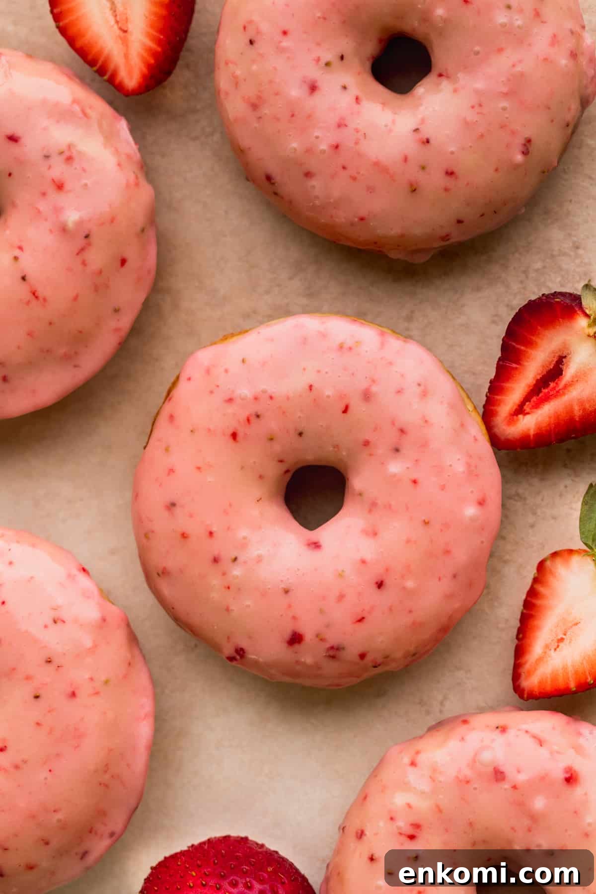 Close up of strawberry glazed donuts with strawberries on the side.
