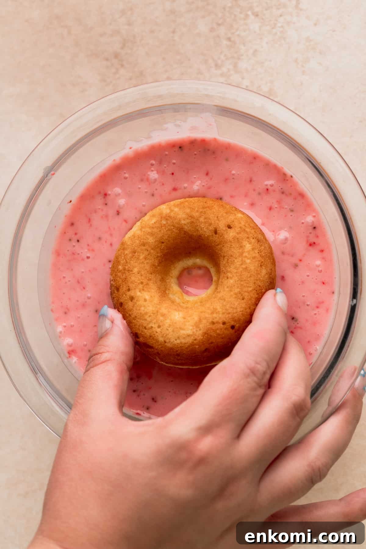 Dipping donut into a glass bowl.