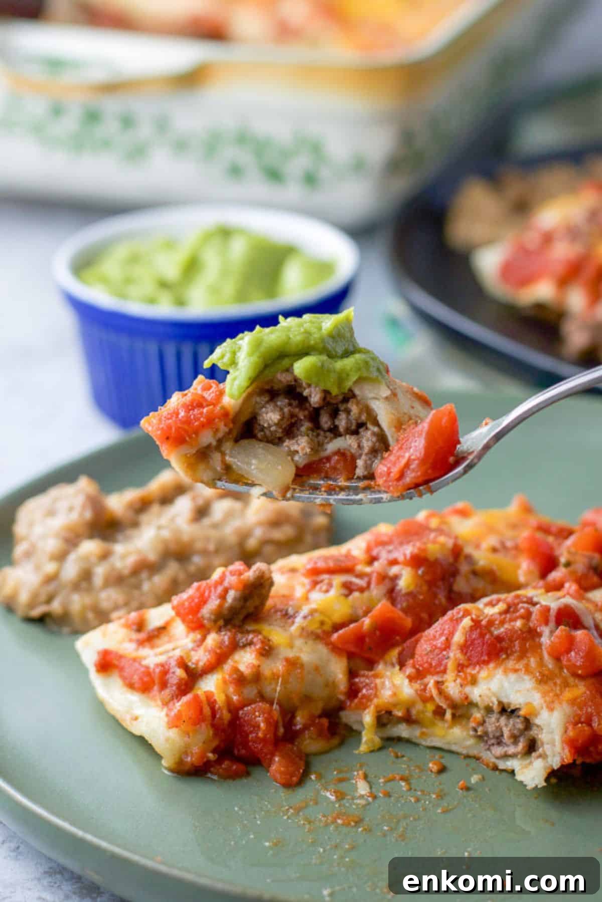 Forkful of a bite of beef enchiladas ready to be eaten.