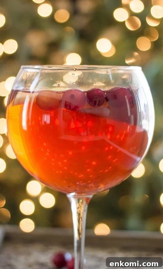 A glass of Christmas sangria with cranberries and apple slices.