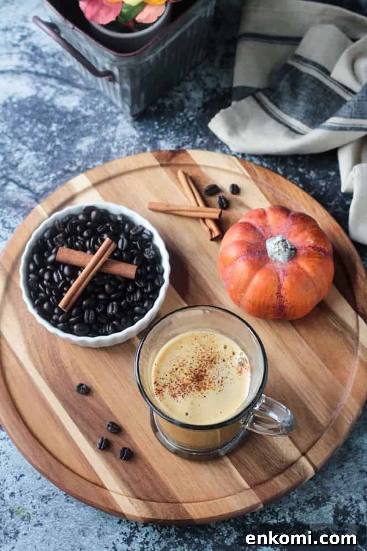 Harvest Oat Pumpkin Latte - a creamy, dairy free coffee drink perfect for sipping this fall. Made with real pumpkin and no refined sugar, this delicious beverage is a indulgent treat you can feel good about. Tastes like your favorite pumpkin spice latte! Overhead view of a latte on a round board with a bowl of coffee beans.