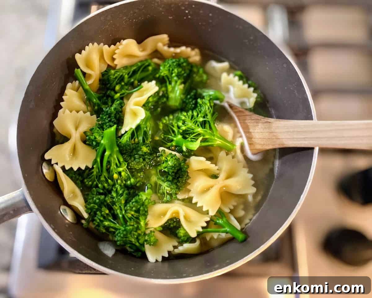 Broccoli cooking with noodles in a pan on the stove