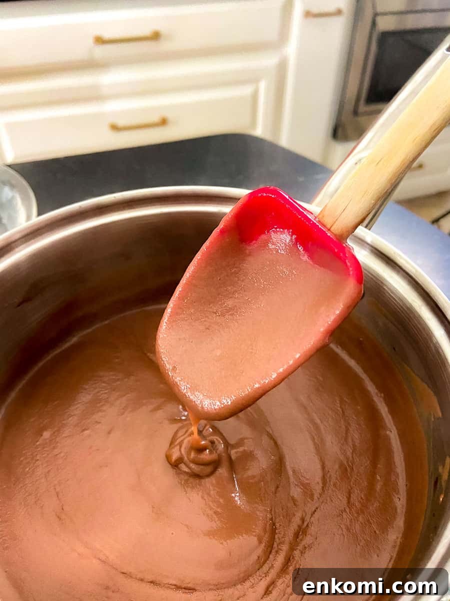 Chocolate pie filling in saucepan sticking to a red spoon