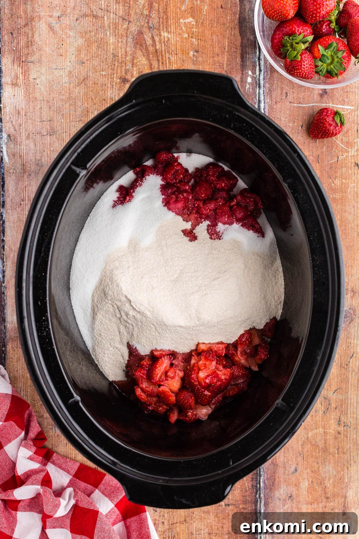 Strawberries, raspberries, pectin and sugar in the crock of a slow cooker.