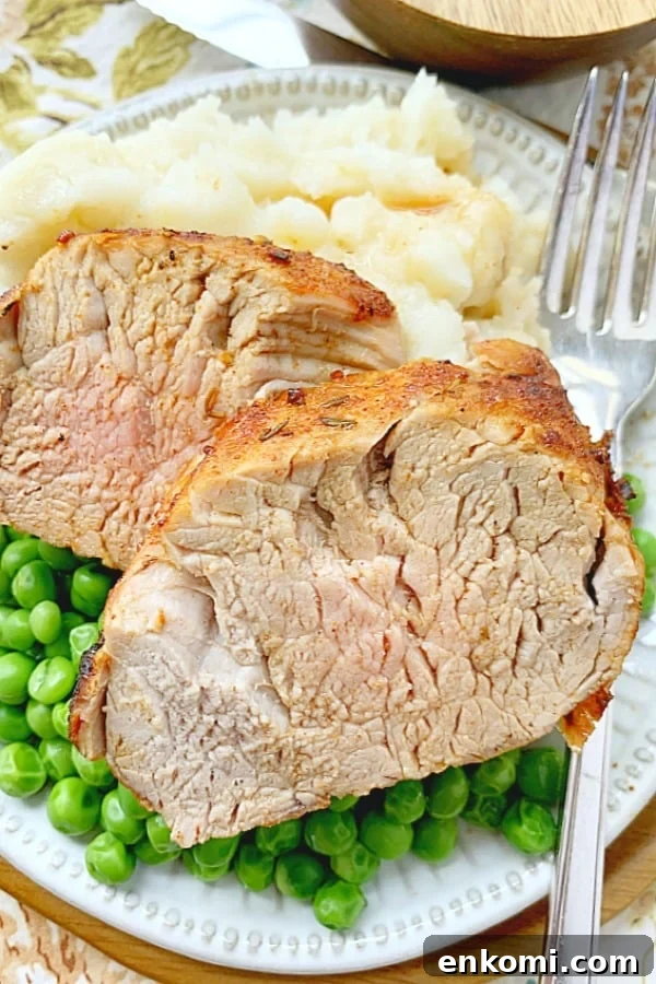 pork tenderloin sliced on a plate with potatoes and peas