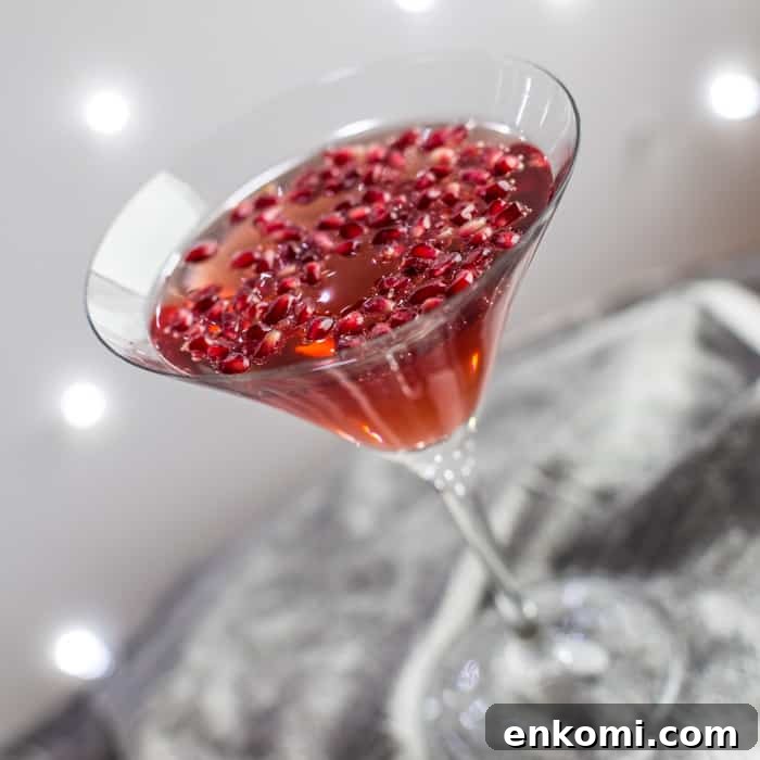 a cocktail glass on a silver tray filled with Pomagranate Popper Cocktail