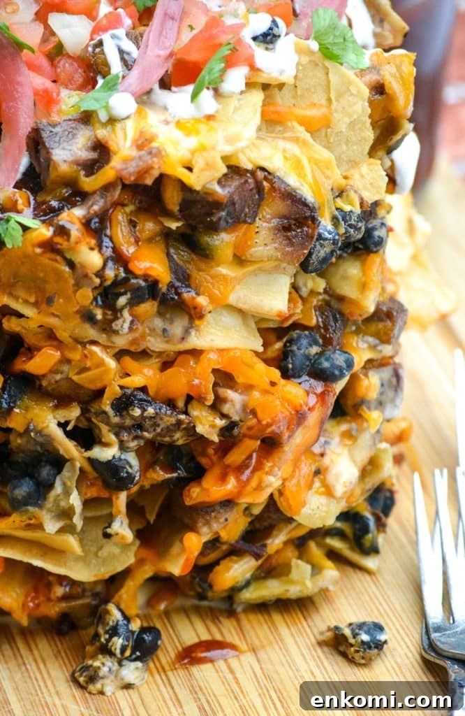Loaded Nachos: How to Make Trash Can Nachos at Home 3 stacked trash can nachos on a wooden cutting board