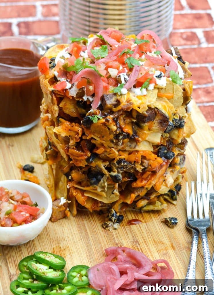 Loaded Nachos: How to Make Trash Can Nachos at Home 5 a stack of trash can nachos with beef brisket on a wooden cutting board