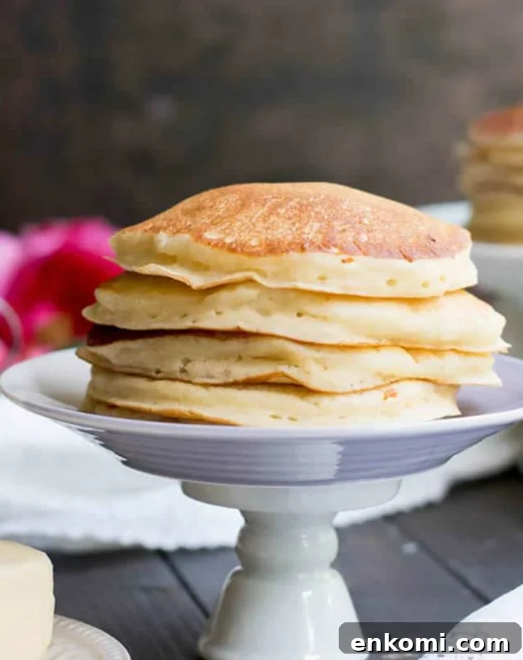 Fluffy Buttermilk Pancakes stacked on a pedestal by themerchantbaker.com