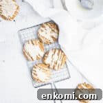 brown butter iced pumpkin cookies on a small silver cooling rack next to a piece of white linen and a bowl.