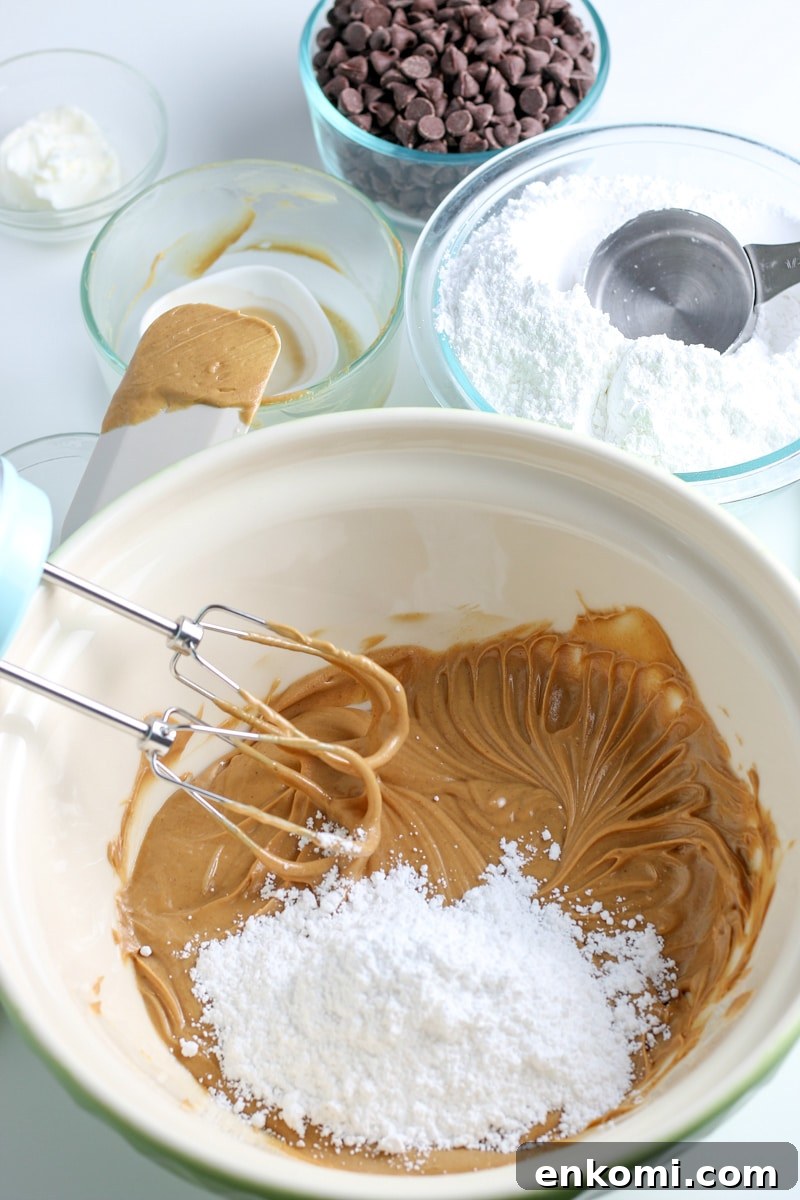 Classic Old-Fashioned Peanut Butter Balls Recipe 5 peanut butter and butter mixture with powdered sugar in a white mixing bowl.