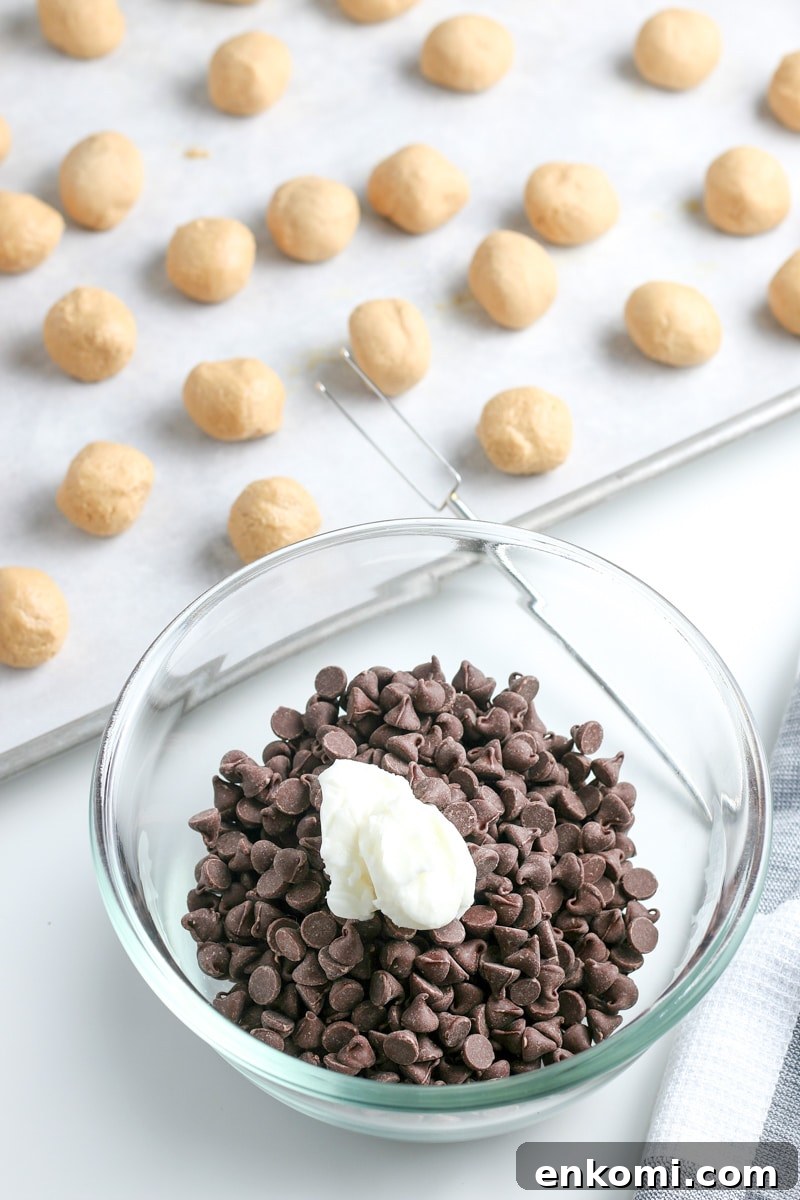 Classic Old-Fashioned Peanut Butter Balls Recipe 7 chocolate chips and vegetable oil in a small glass bowl and peanut butter balls on a baking sheet with parchment paper.