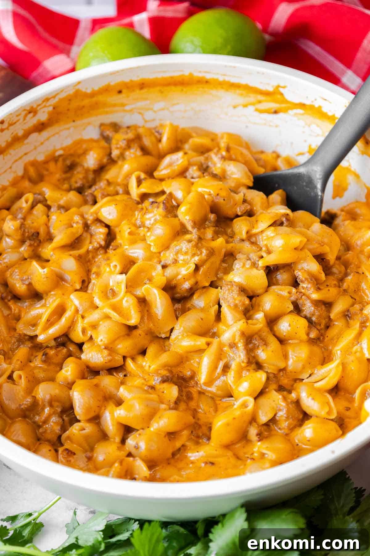 A skillet full of taco mac and cheese, with a serving spoon ready to serve the dish.