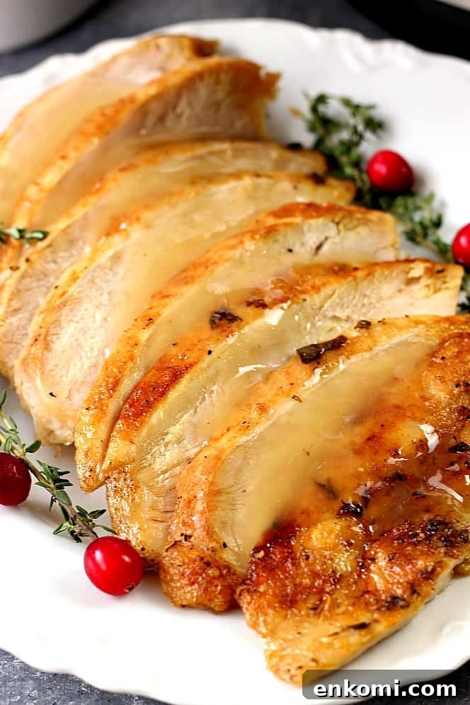 Side shot of sliced turkey breast with gravy on white platter.
