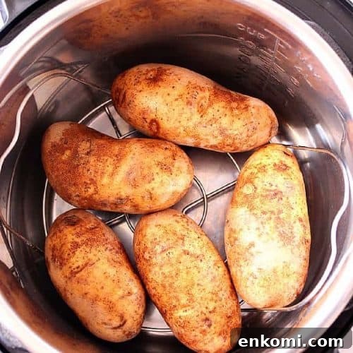 Square image of four Russet potatoes on a rack in the Instant Pot pressure cooker.