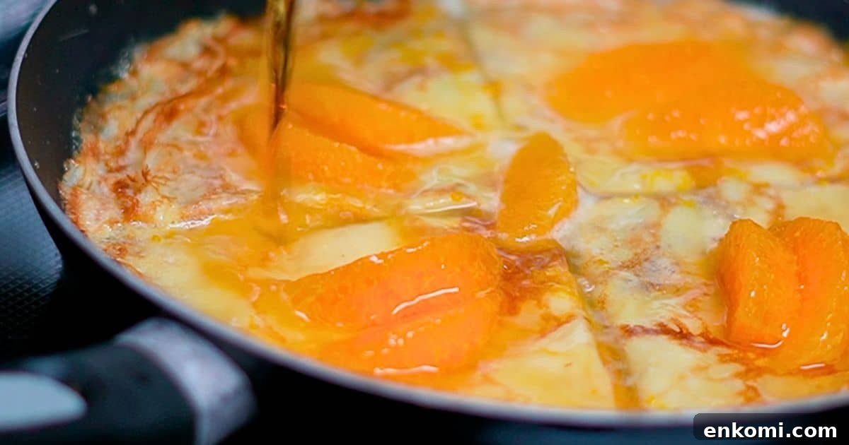 pouring grand marnier over the crepes and orange slices in a frying pan