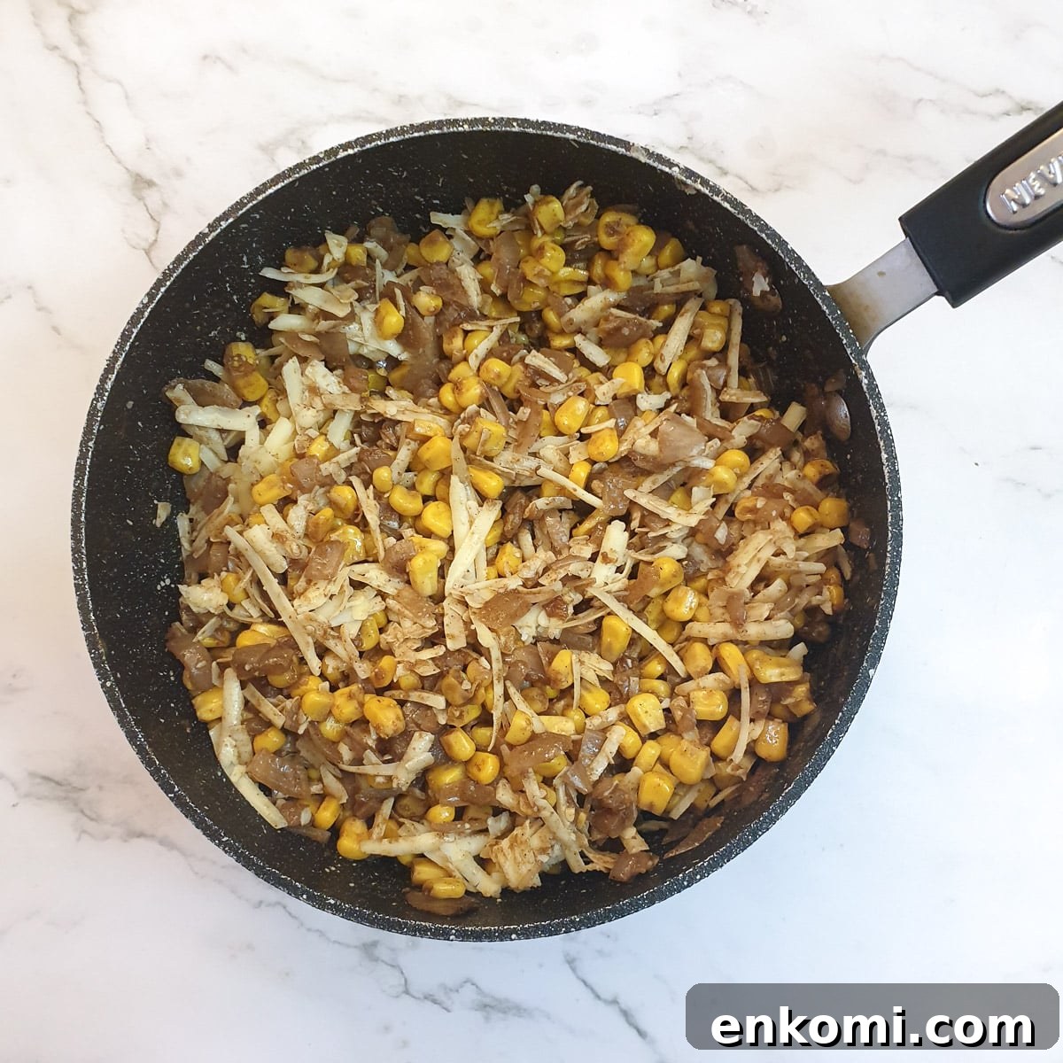 Grated cheese mixed into the cooled sweetcorn filling in a frying pan.