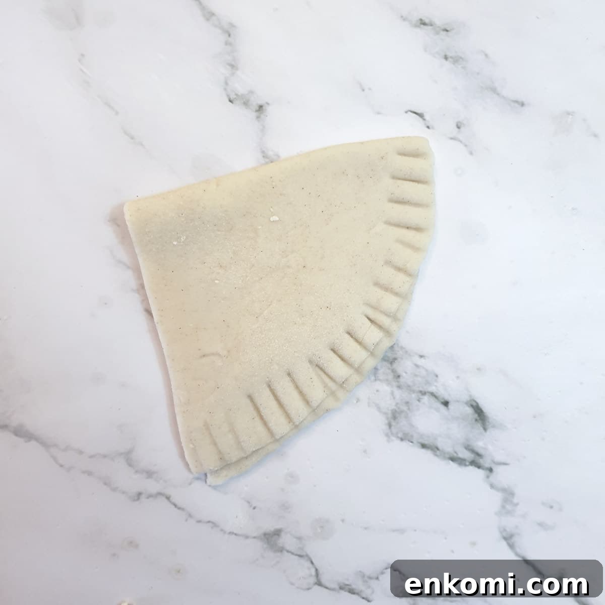 A semi-circle of pastry folded in half and sealed on one side, leaving the top open.